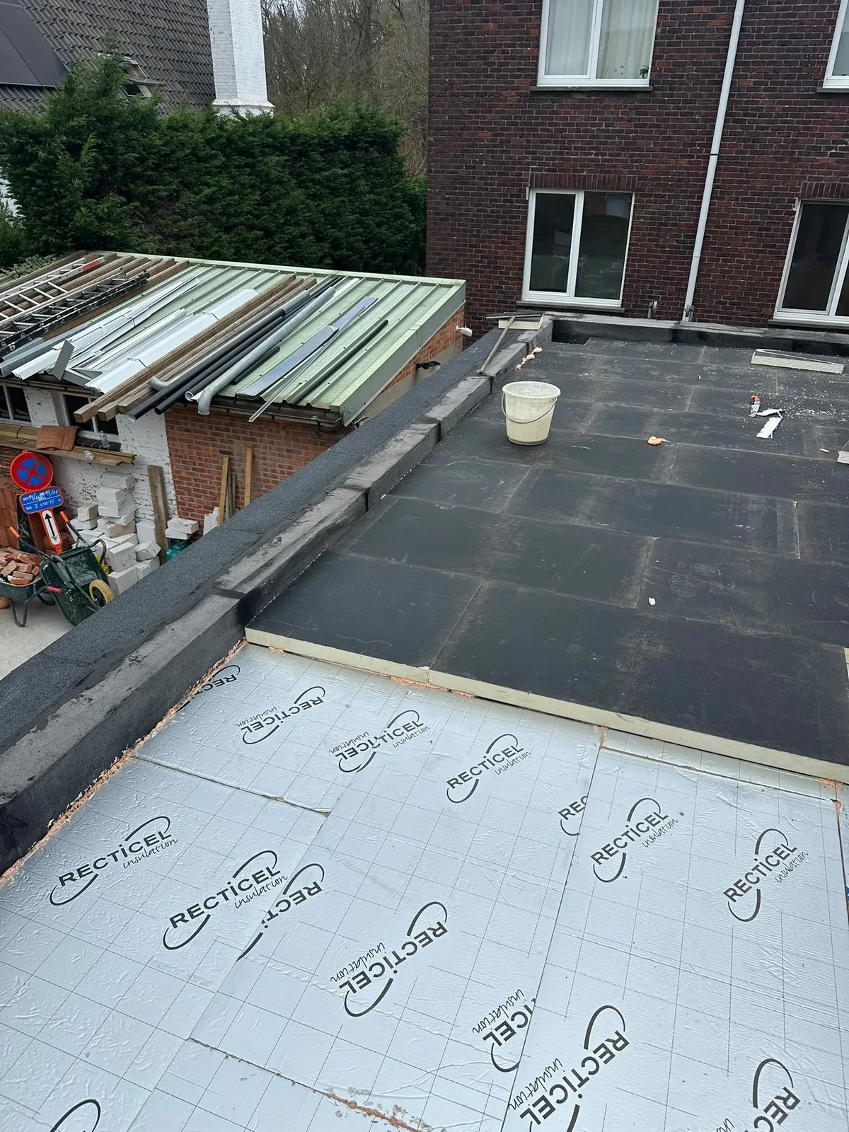 Plat dak in uitvoering: isolatieplaten naast al afgewerkte roofing