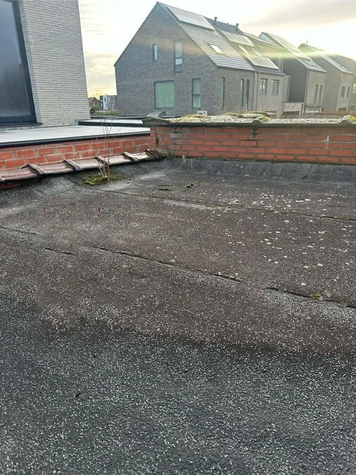 Verouderd plat dak met oude bitumen en grind, voor vernieuwing